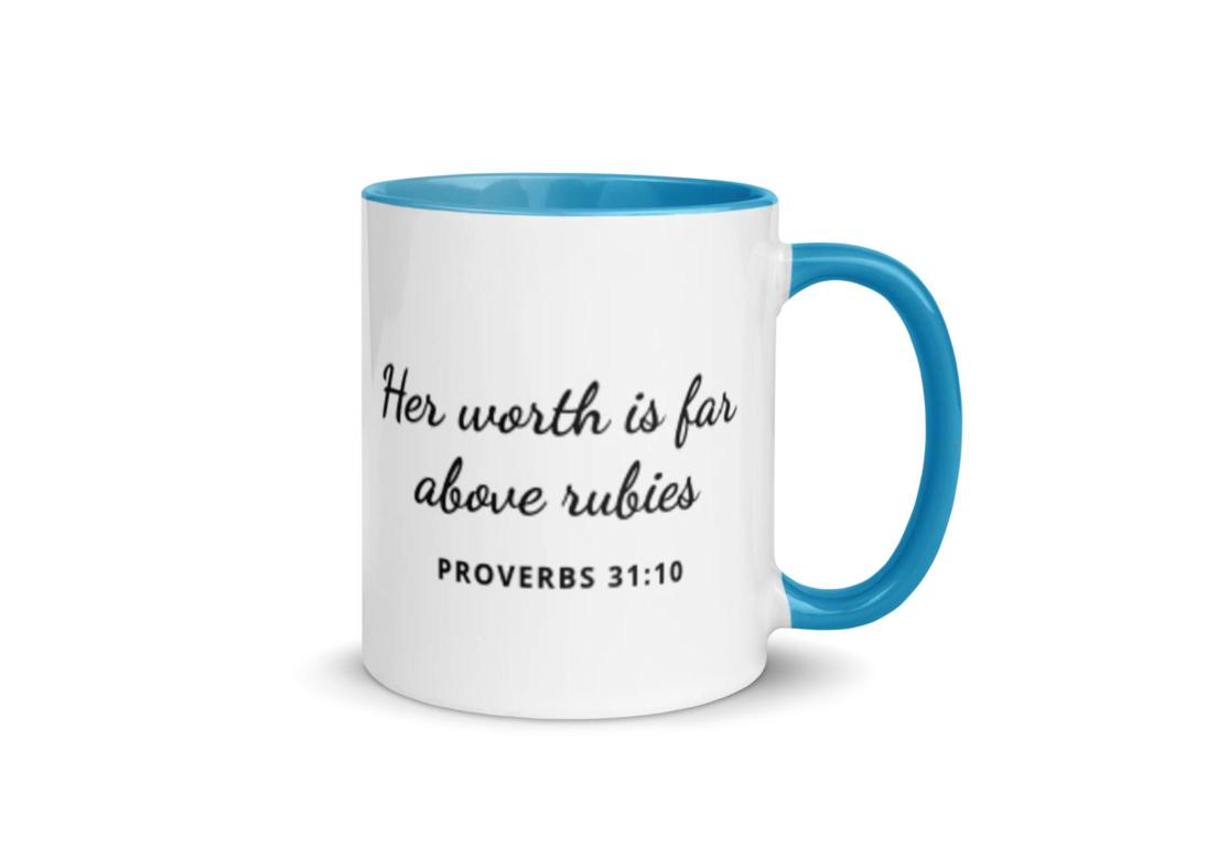 White ceramic mug with blue handle and interior, black script text "Her worth is far above rubies," Proverbs 31:10