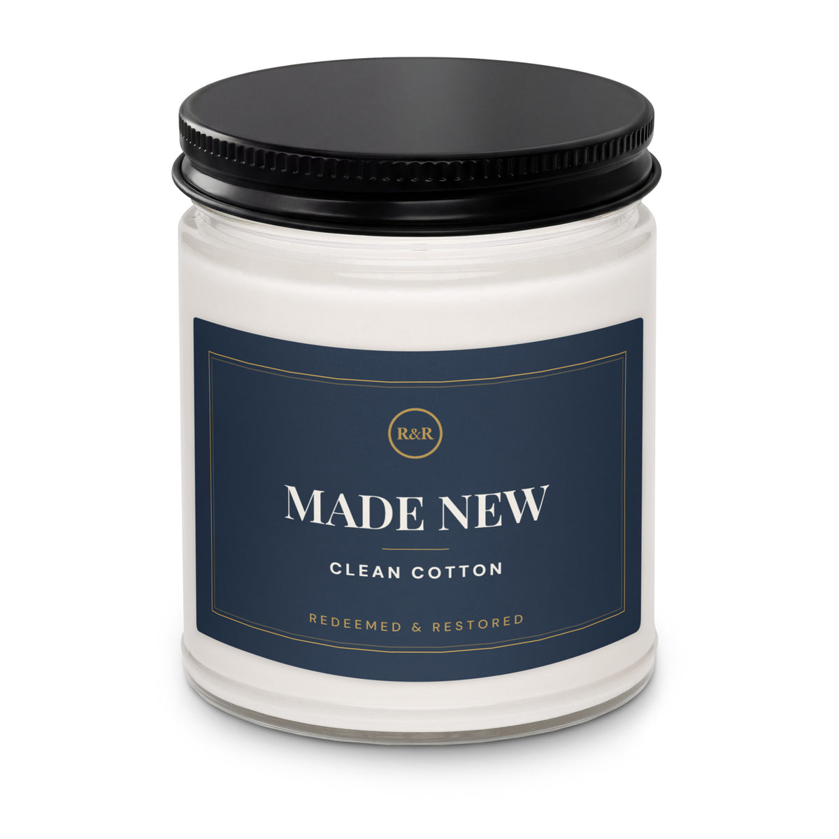 Close-up of the Made New candle jar with black lid, showing the navy label with gold border and Clean Cotton scent name