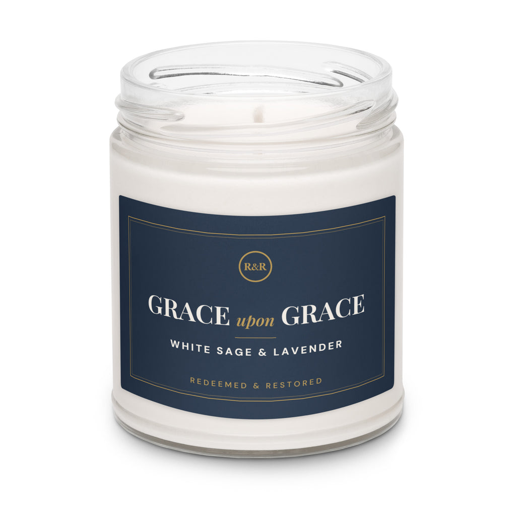 Grace Upon Grace White Sage & Lavender soy candle with the lid removed, showing white wax and wick in a clear glass jar
