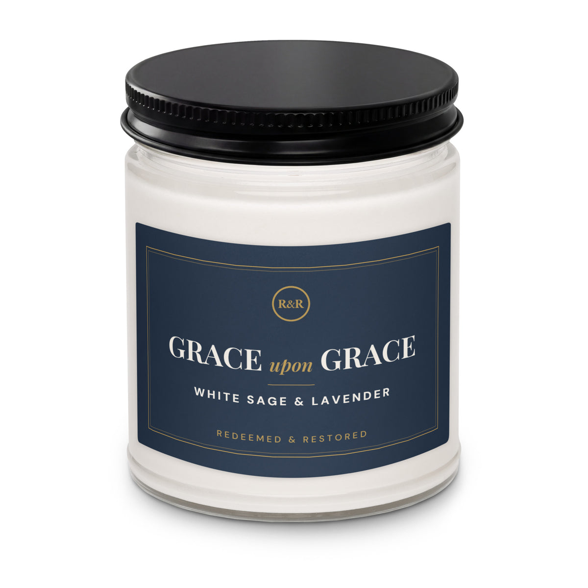 Close-up of the Grace Upon Grace candle jar with black lid, showing the navy label with gold border and White Sage & Lavender scent name